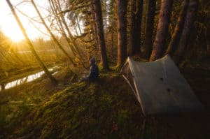 shows a backpacker sitting next to a single walled tent