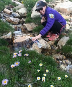 girl filling smartwater bottle out of a creek