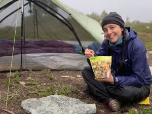 shows a hiker eating a freeze dried backpacking meal