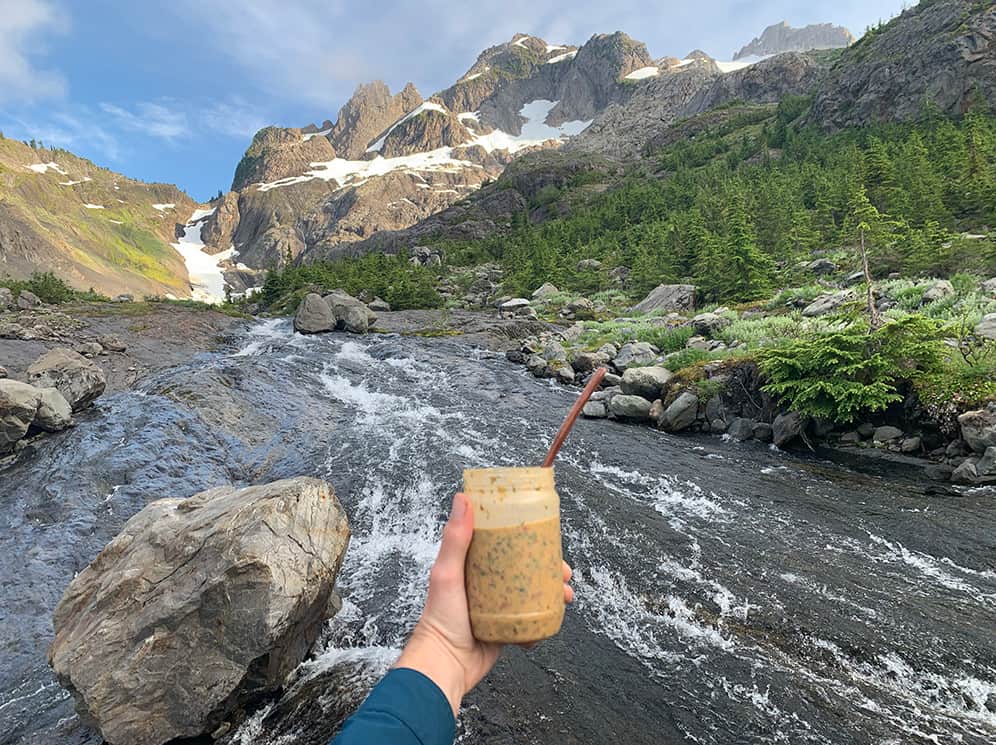 hiker holding a stoveless backpacking meal in a cold soak container