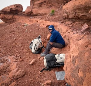 shows a hiker sitting next to there backpack