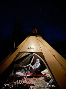 Hunter sitting on an ultralight camp chair inside of a hot tent. 
